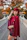 A person wrapped in a flowing handmade long cape, walking through a leafy park in autumn.