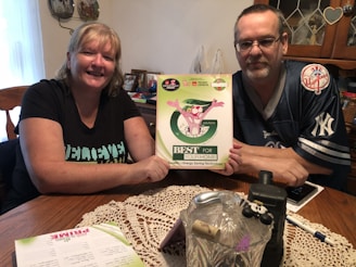 A smiling couple reviewing a cash offer document at a kitchen table.