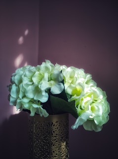 Luxurious bouquet in muted tones placed on a white surface with soft shadows and gold accents.