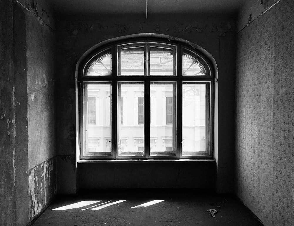 grayscale photo of window with white curtains