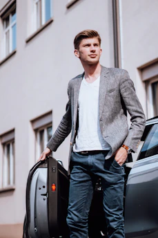 A smartly dressed chauffeur opening a car door for a passenger in a busy Chennai street.
