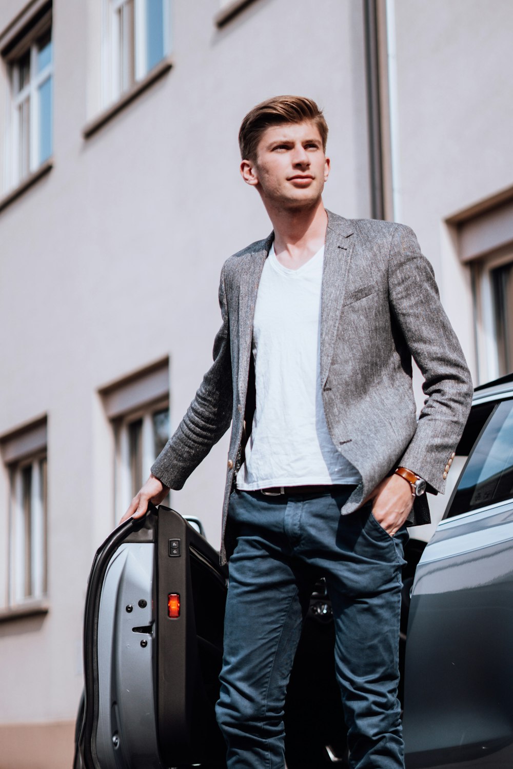 man in gray blazer standing beside black car