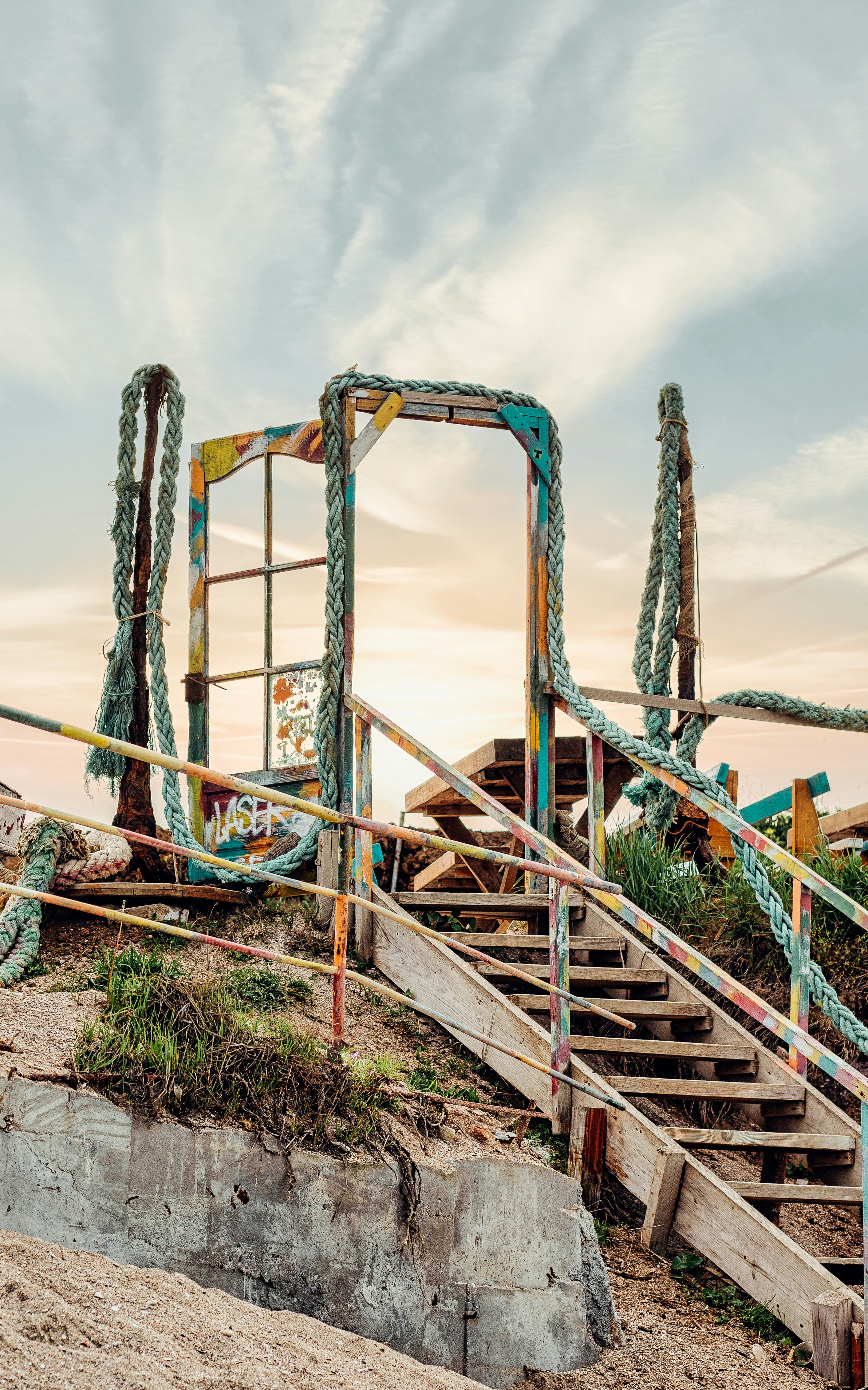 Escalera de metal verde en arena marrón cerca del cuerpo de agua durante el día