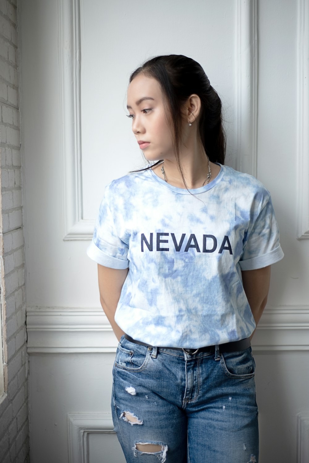 woman in white crew neck t-shirt and blue denim shorts standing beside white wooden door