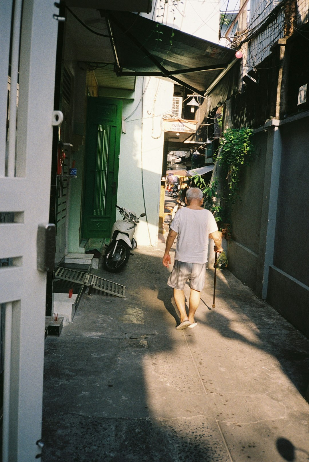 man in yellow t-shirt and brown pants walking on sidewalk during daytime