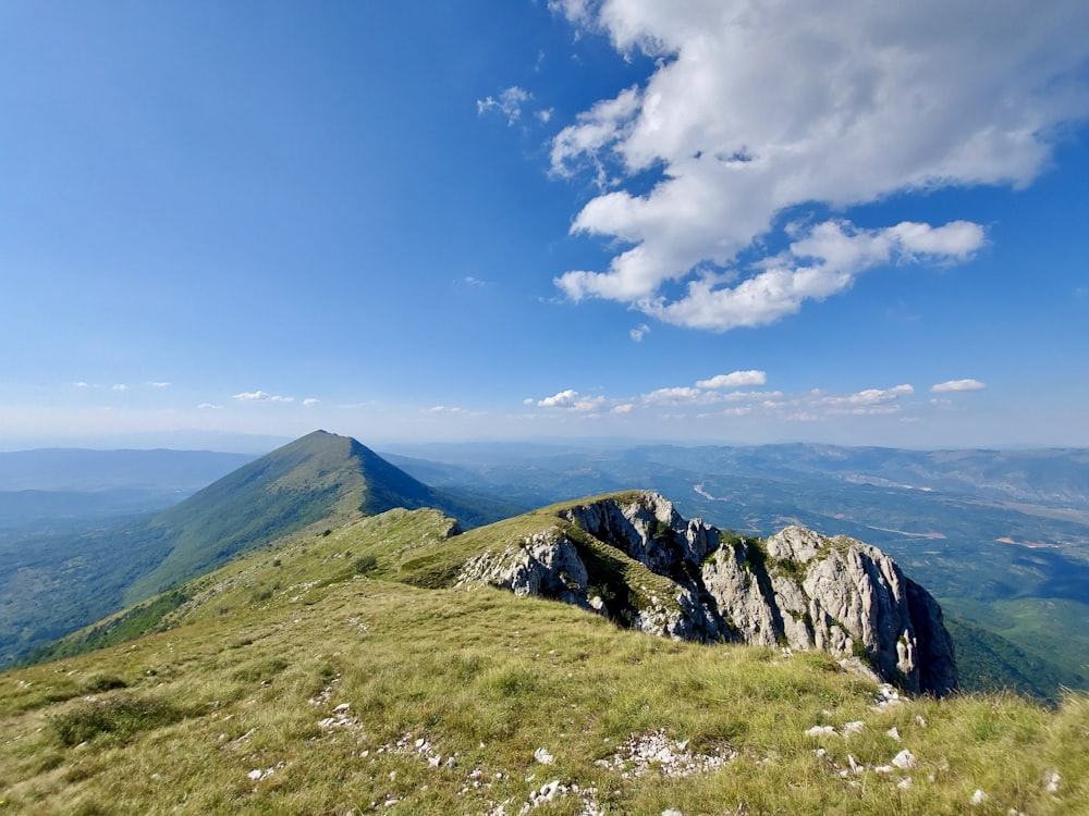 green grass field and mountain under blue sky during daytime