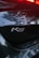 Close-up of a car's rear displaying the K5 badge with reflections of trees and light from the surroundings visible on the glossy surface.
