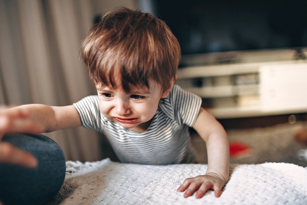 boy in black and white striped crew neck t-shirt sitting on white and gray bed