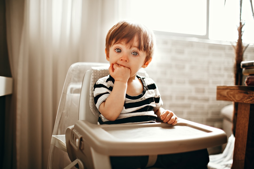 boy in black and white stripe shirt sitting on white plastic chair