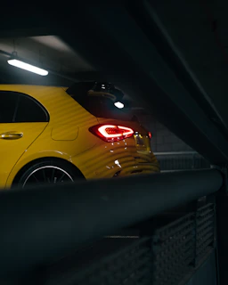 A shining used car parked in a dim garage lit with yellow strip lights.