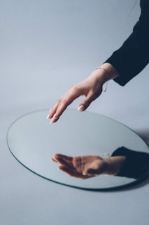 person in black long sleeve shirt holding round glass