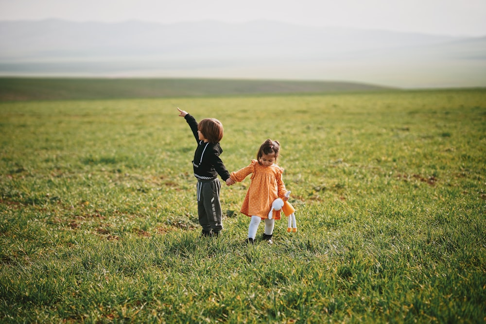 낮 동안 푸른 잔디밭을 걷는 주황색 드레스를 입은 소녀