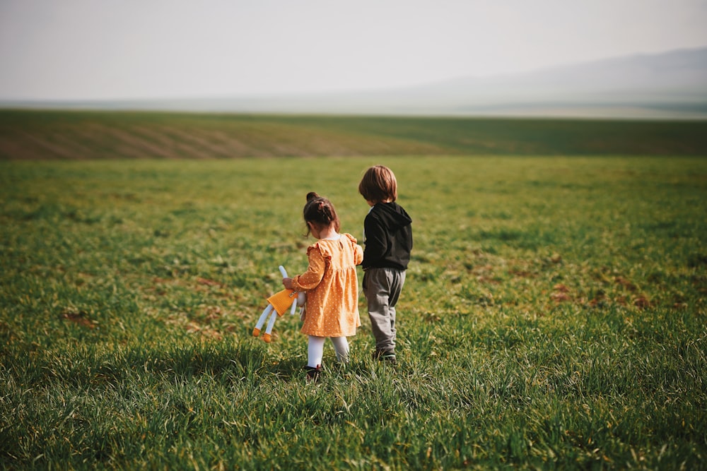 昼間の緑の芝生の上を歩く男の子と女の子