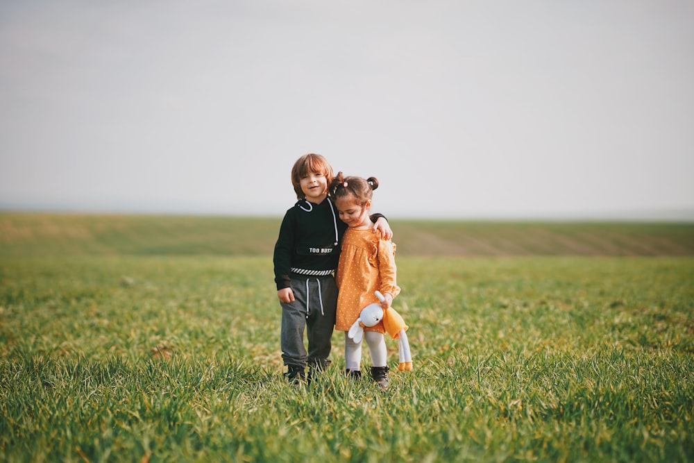 woman in black long sleeve shirt holding girl in orange dress on green grass field during