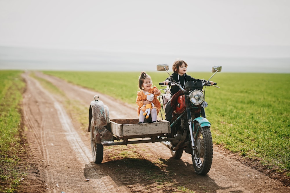 2 boys riding on black motorcycle during daytime