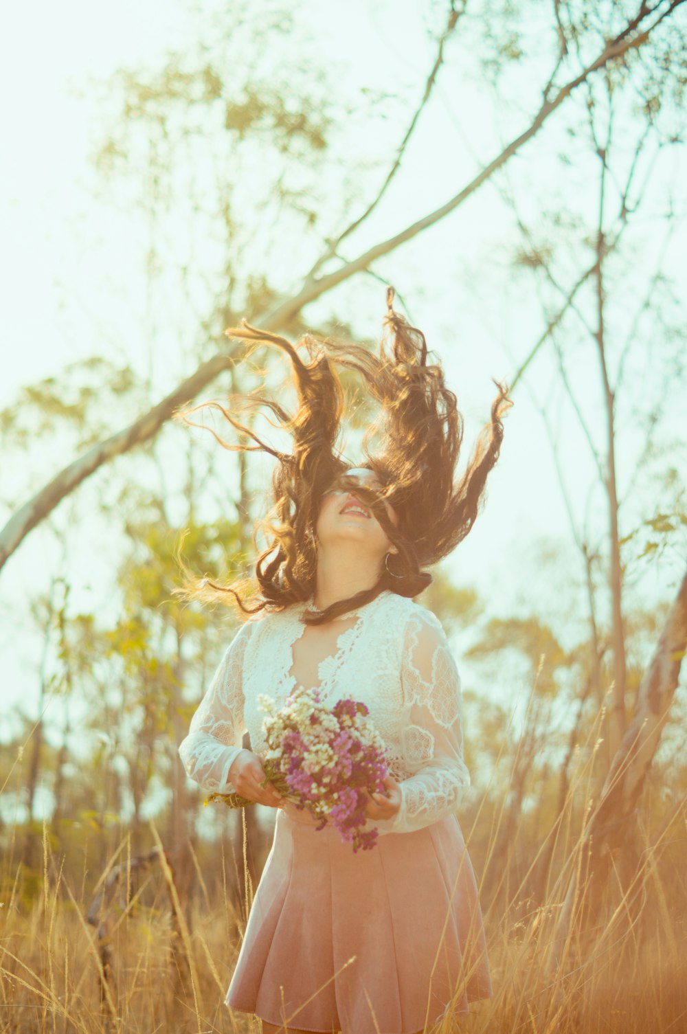 girl in white and pink floral dress standing on brown grass field during daytime