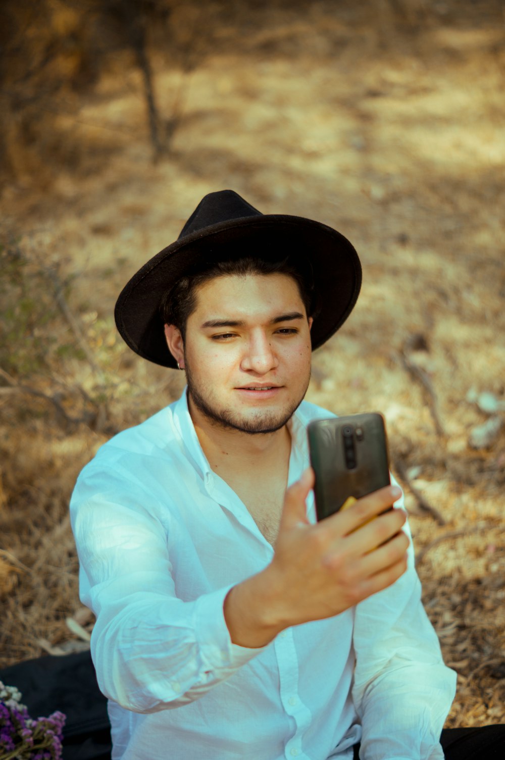 man in white dress shirt holding black smartphone