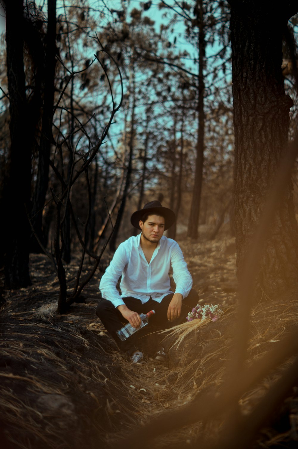 man in white long sleeve shirt sitting on brown tree log during daytime