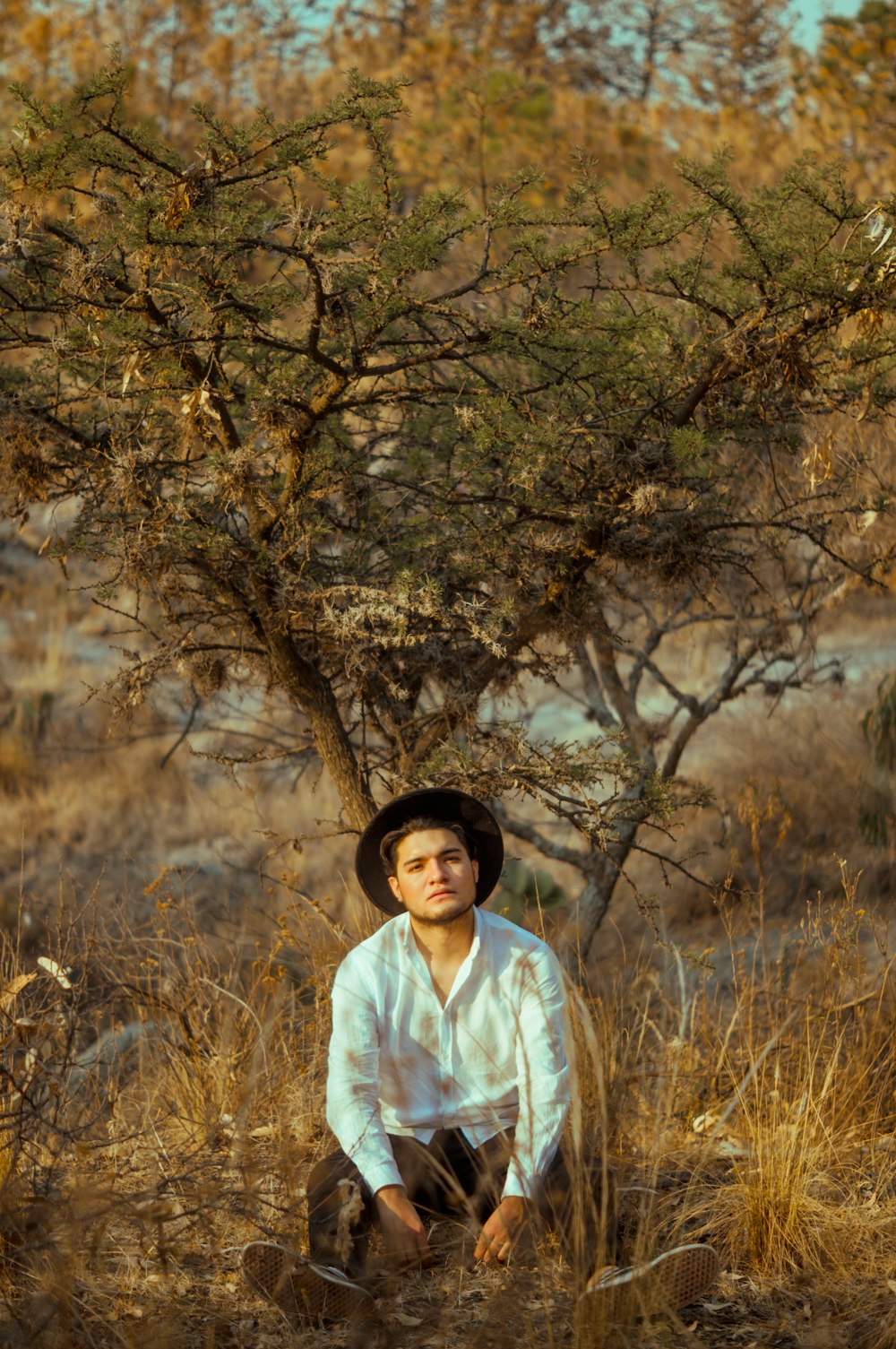 woman in white long sleeve shirt standing near brown tree during daytime