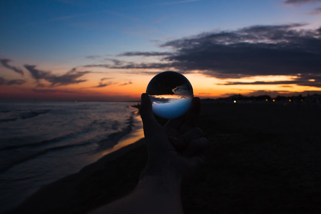 person holding clear glass ball during sunset