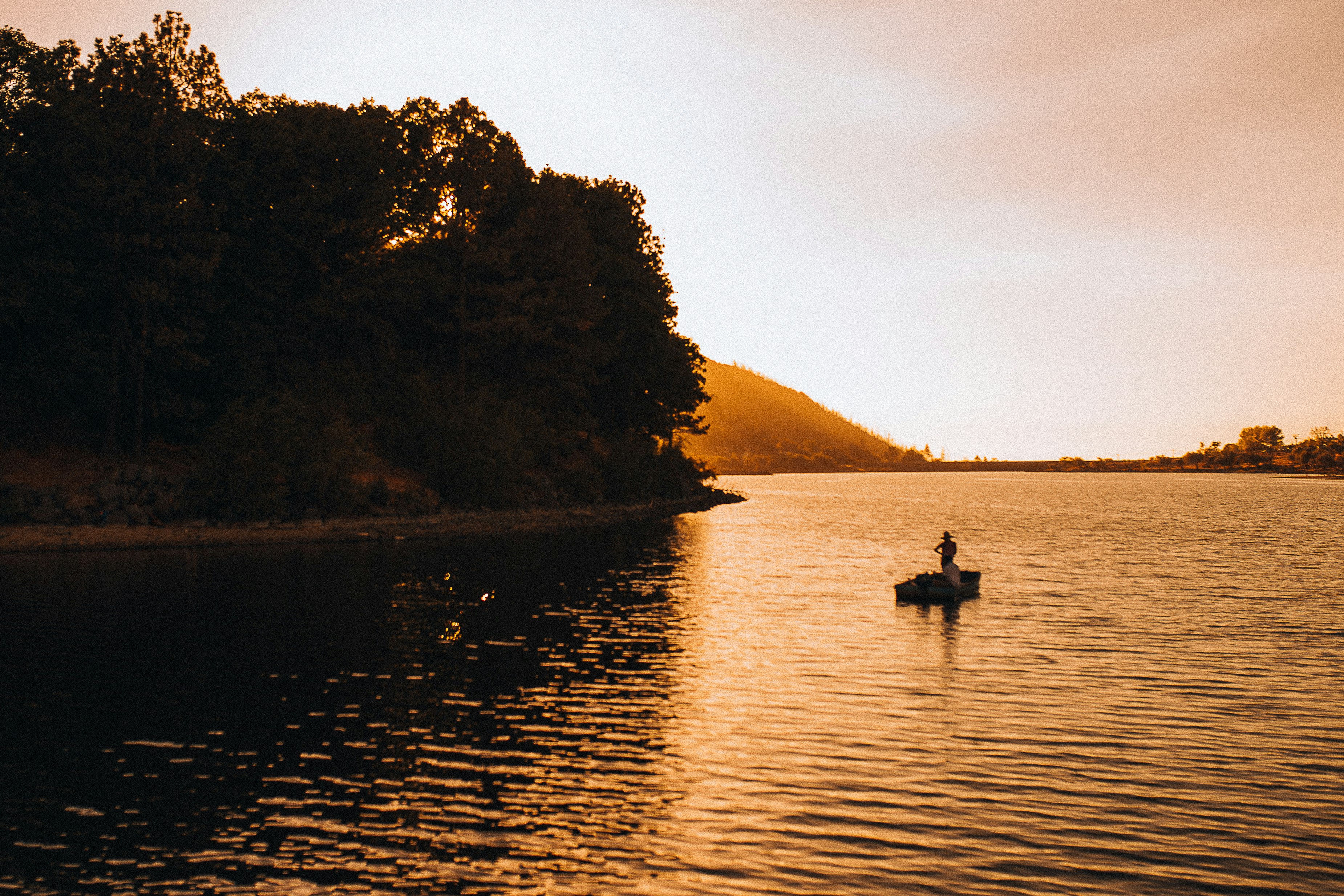 silhouette of 2 people riding on boat on lake during daytime