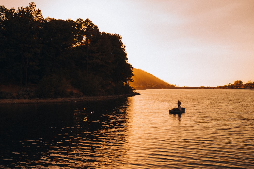 silhueta de 2 pessoas andando no barco no lago durante o dia