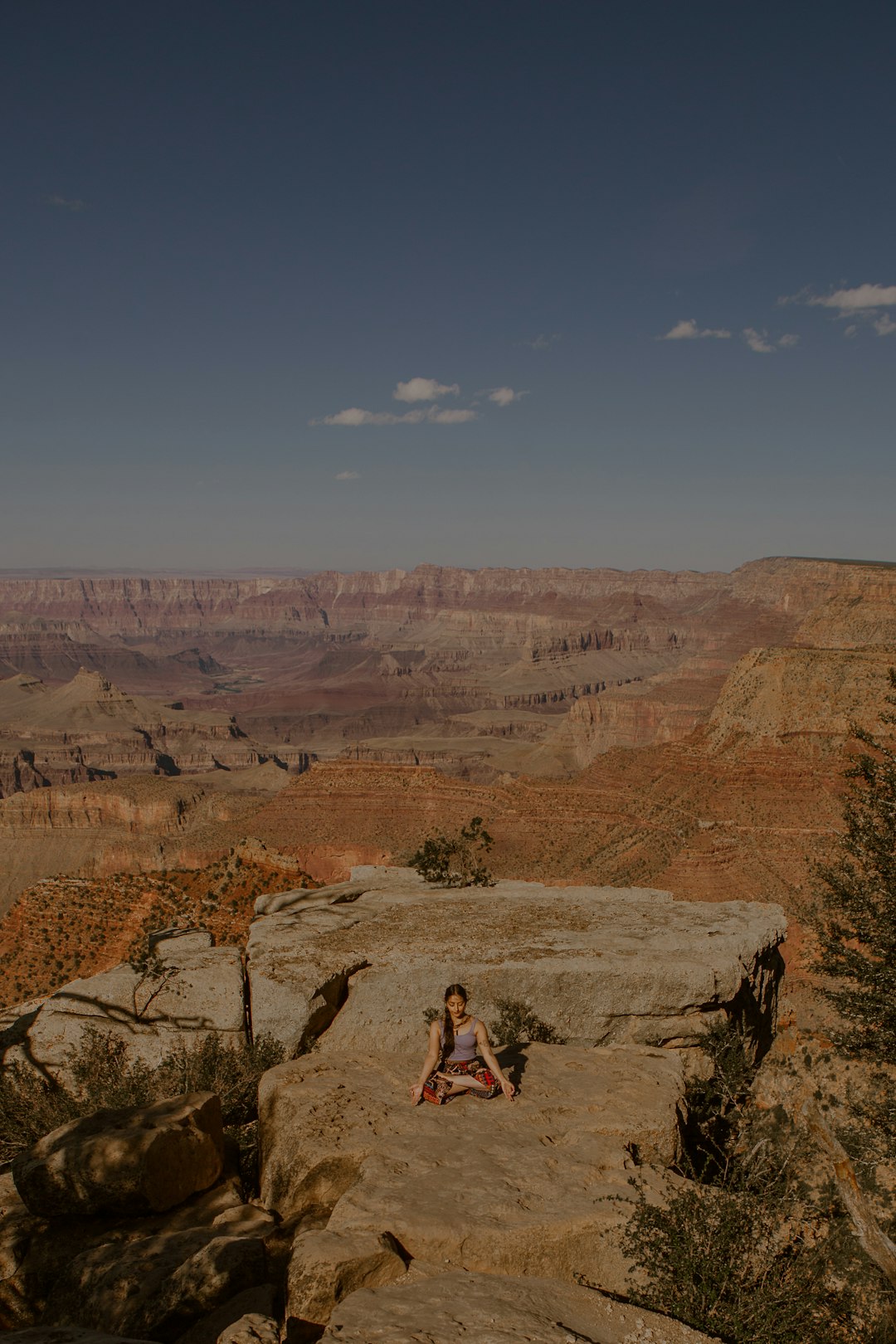 man in black t-shirt and blue denim jeans sitting on rock formation during daytime