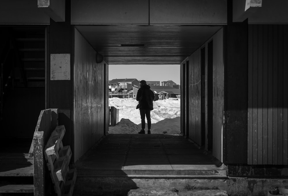 grayscale photo of man and woman walking on hallway