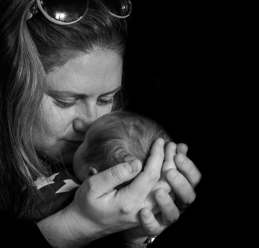 grayscale photo of woman kissing baby