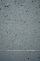 Close-up photo of textured concrete wall with soft shadows highlighting materiality.