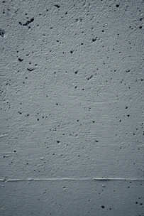 Close-up of textured concrete wall with subtle shadows, evoking strength and stability.