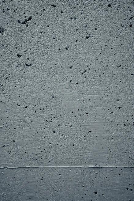 Close-up of textured concrete wall with subtle shadows playing across its surface
