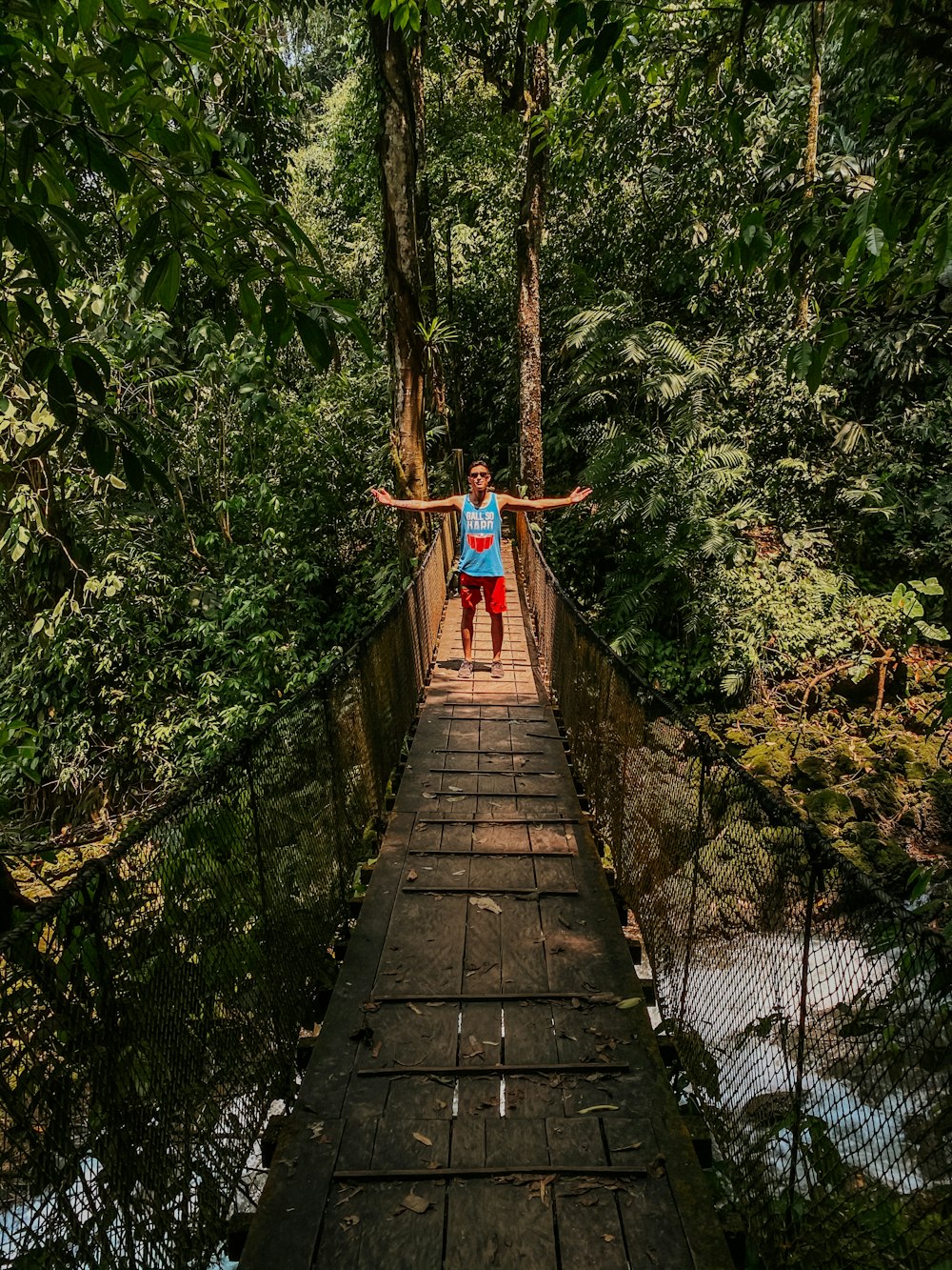 woman in red dress walking on wooden bridge