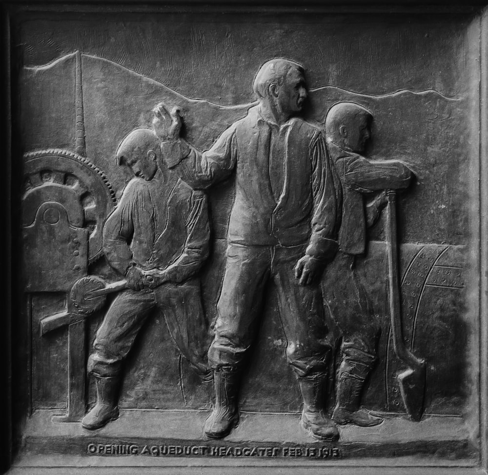 gray scale photo of man and woman statue