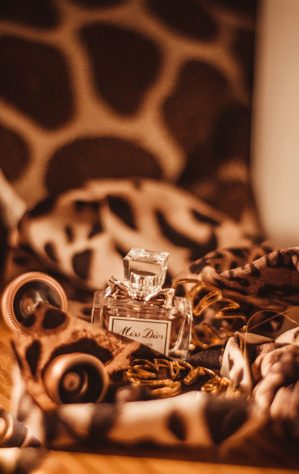 clear glass perfume bottle on brown and black textile