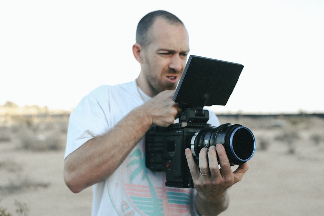 man in white t-shirt holding black camera