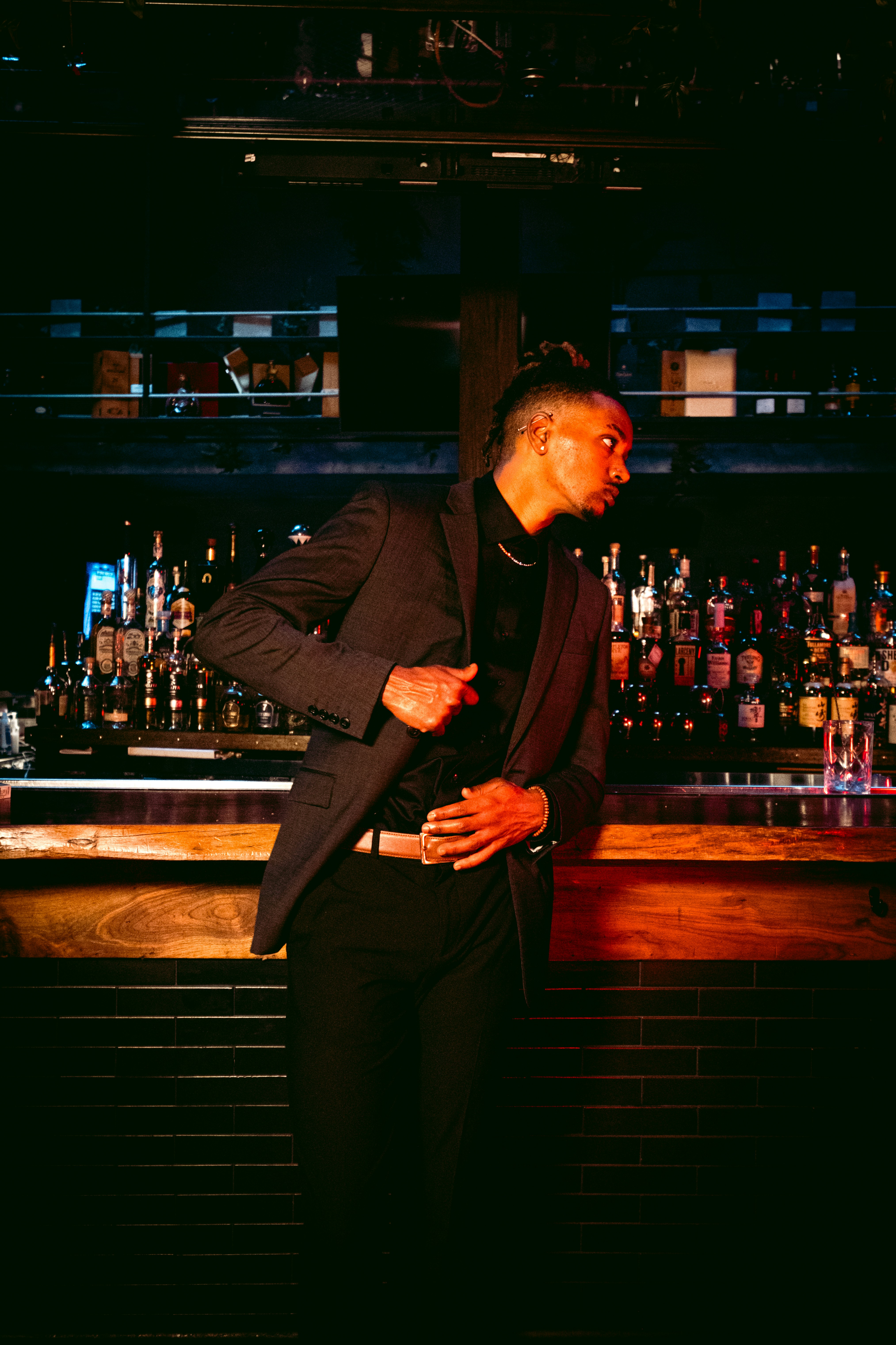 Hombre con traje negro de pie cerca de la barra del bar