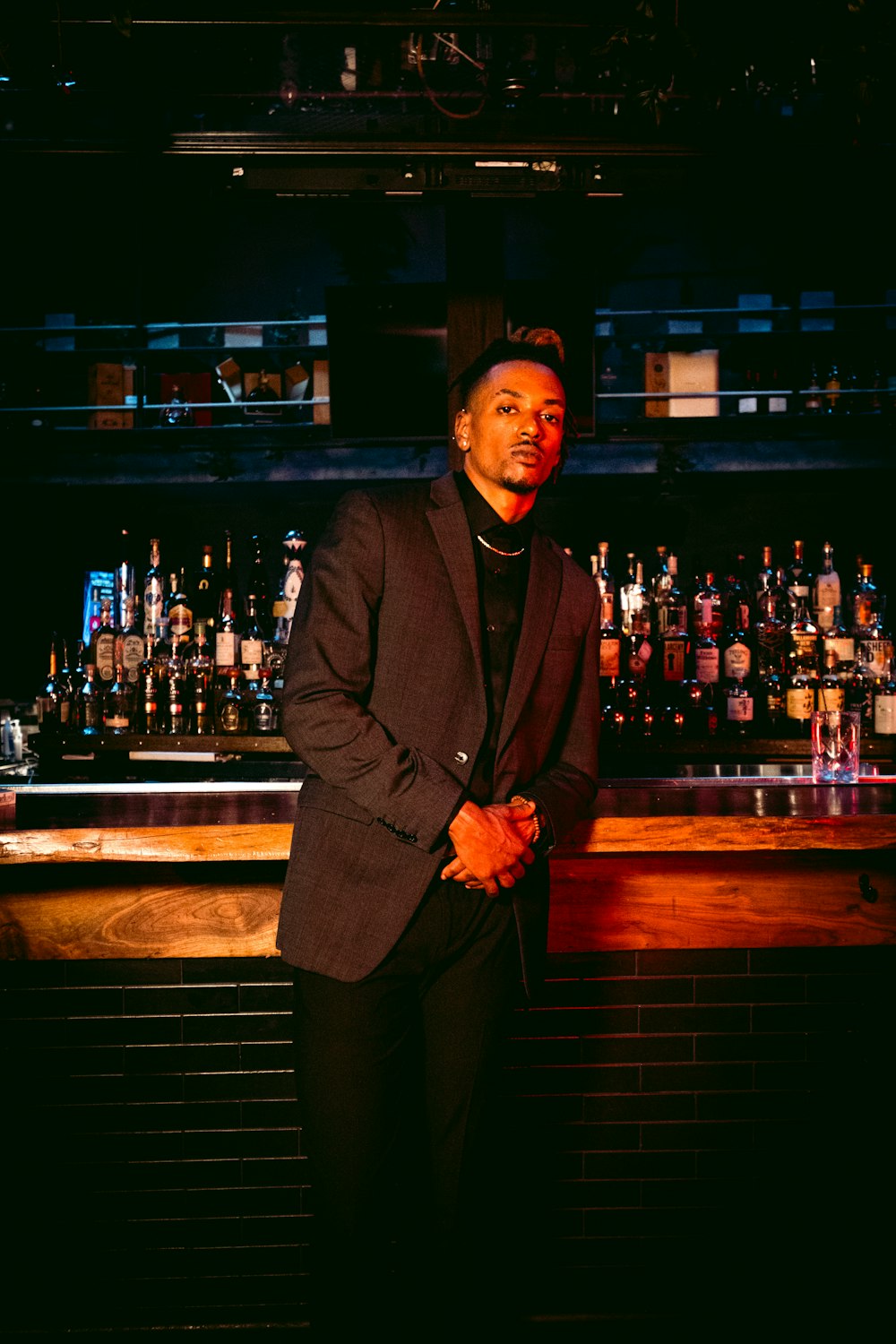 man in black suit standing beside brown wooden bar counter