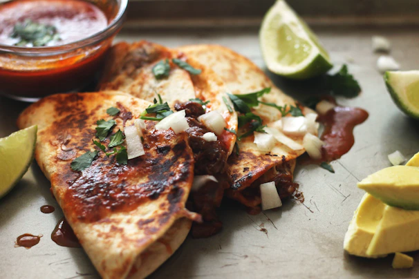 Close-up of a freshly made torta milanesa with melted quesillo and vibrant toppings.