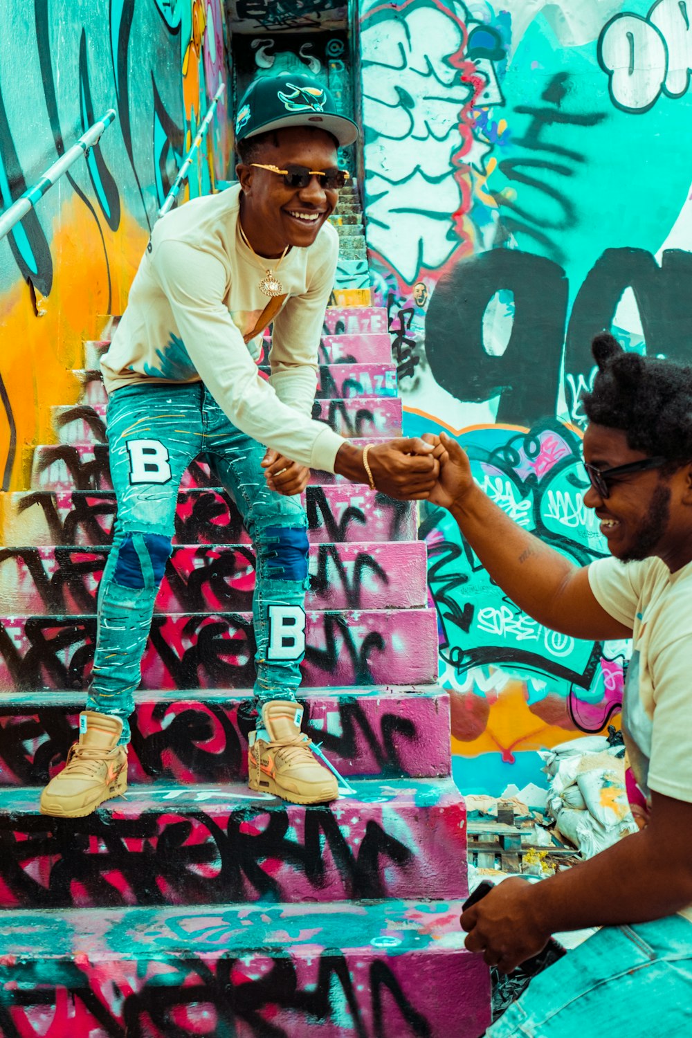 man in white dress shirt and blue denim jeans standing beside graffiti wall