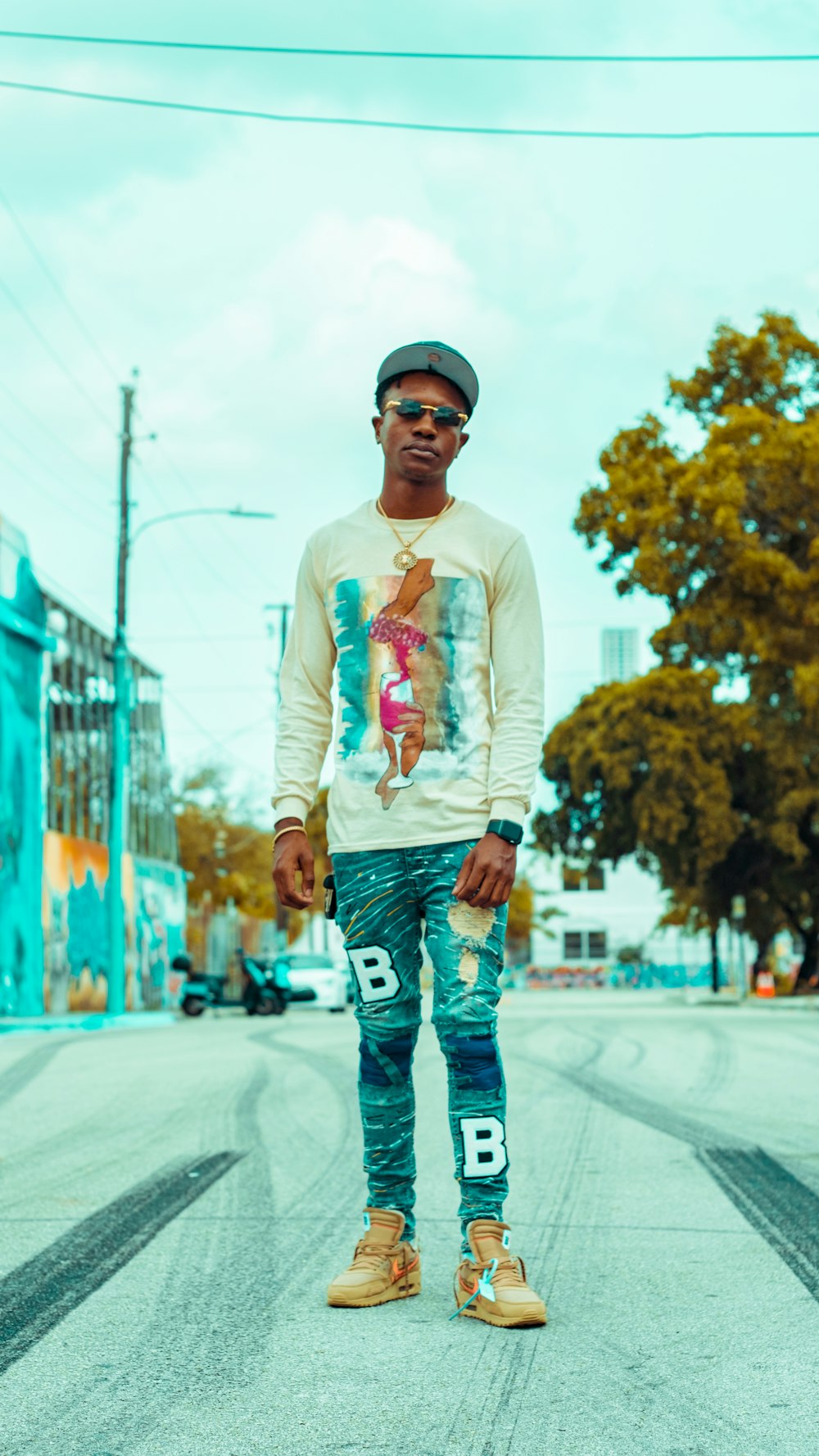 man in white long sleeve shirt and blue denim jeans wearing black sunglasses standing on road