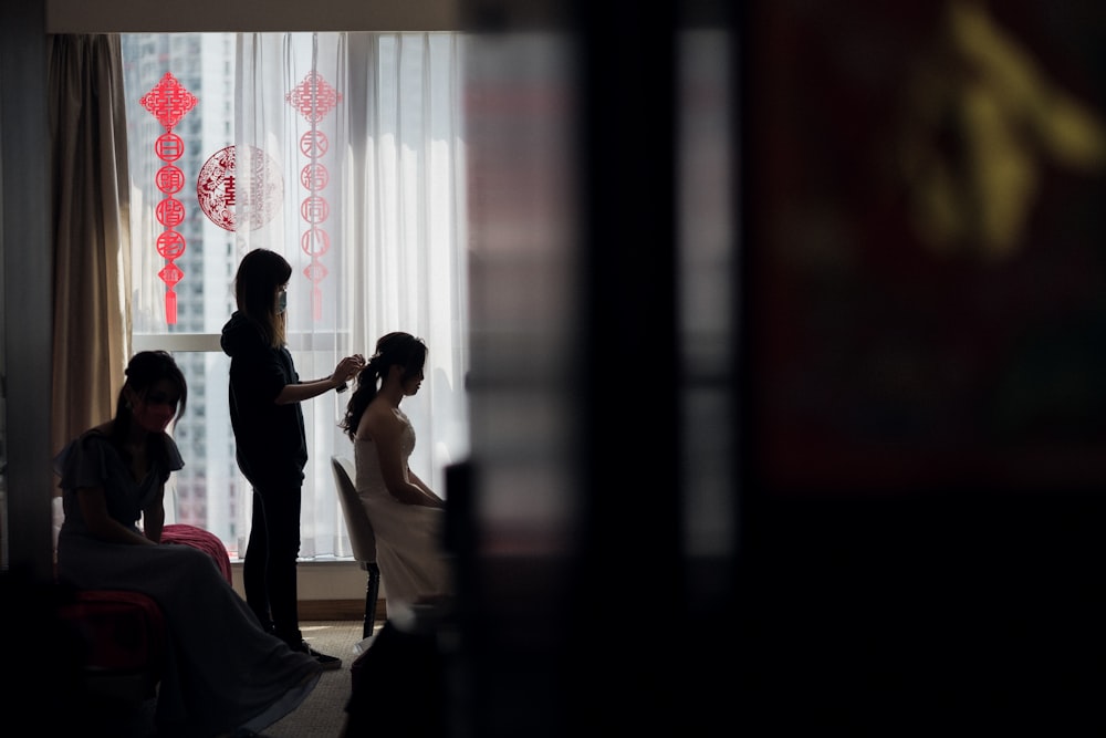 man and woman kissing in front of window