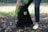 A person wearing gloves picking up dog waste in a clean, green backyard.