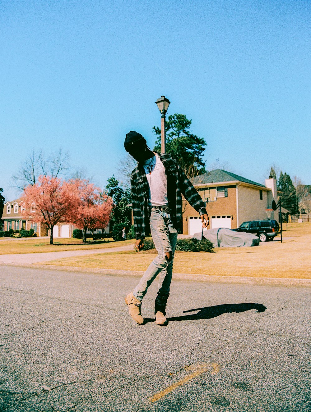 man in black jacket and gray pants walking on gray asphalt road during daytime