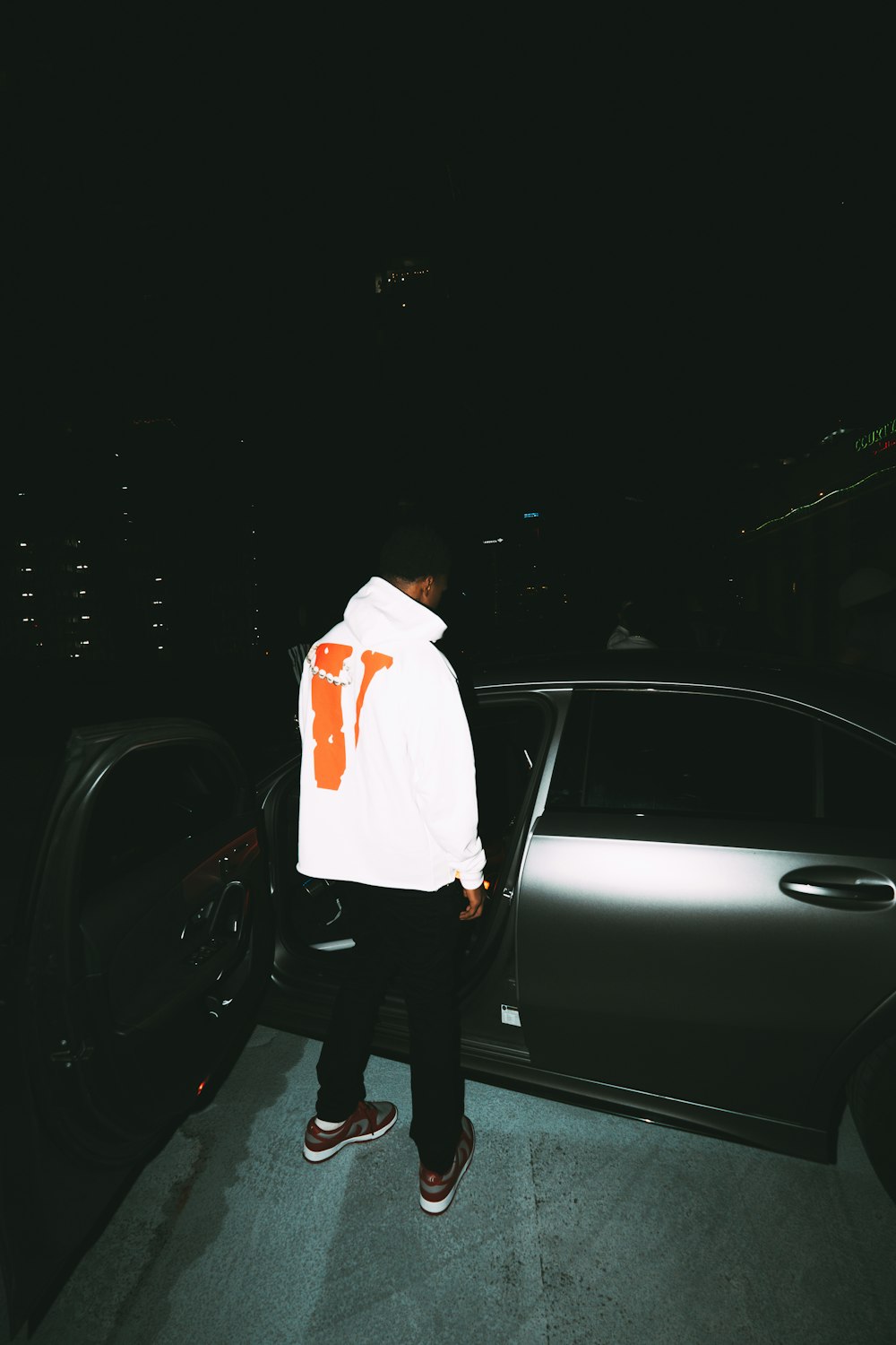 man in white dress shirt and black pants standing beside silver car