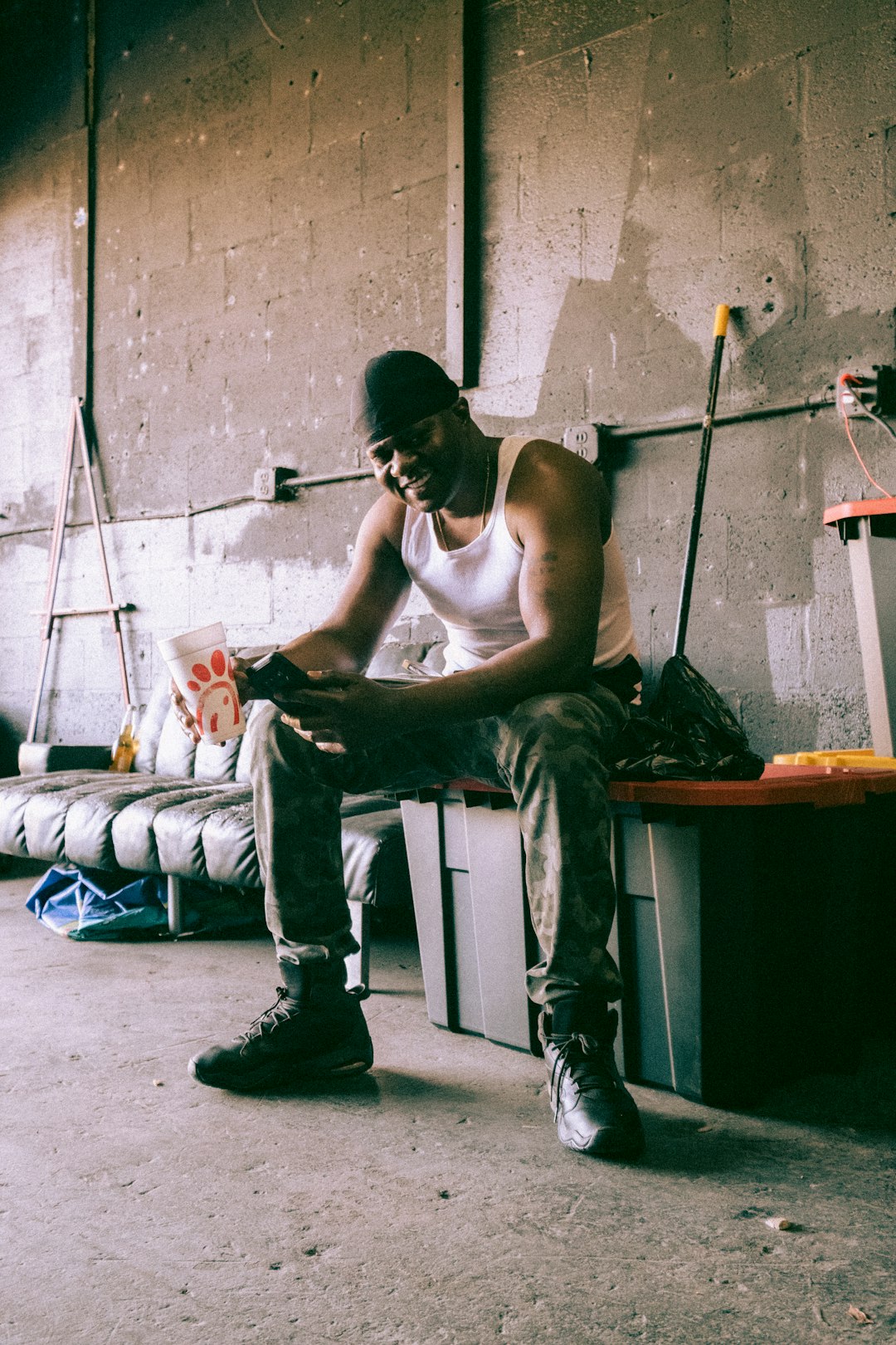 man in white tank top and gray pants sitting on blue bed