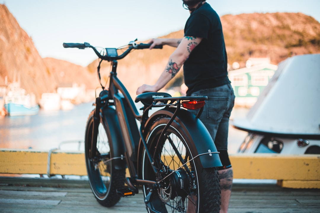 man in black long sleeve shirt and blue denim jeans riding on black bicycle during daytime