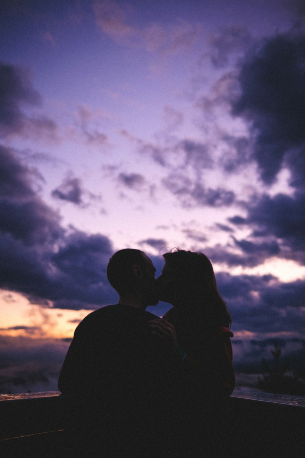 silhouette of man and woman kissing under cloudy sky during daytime