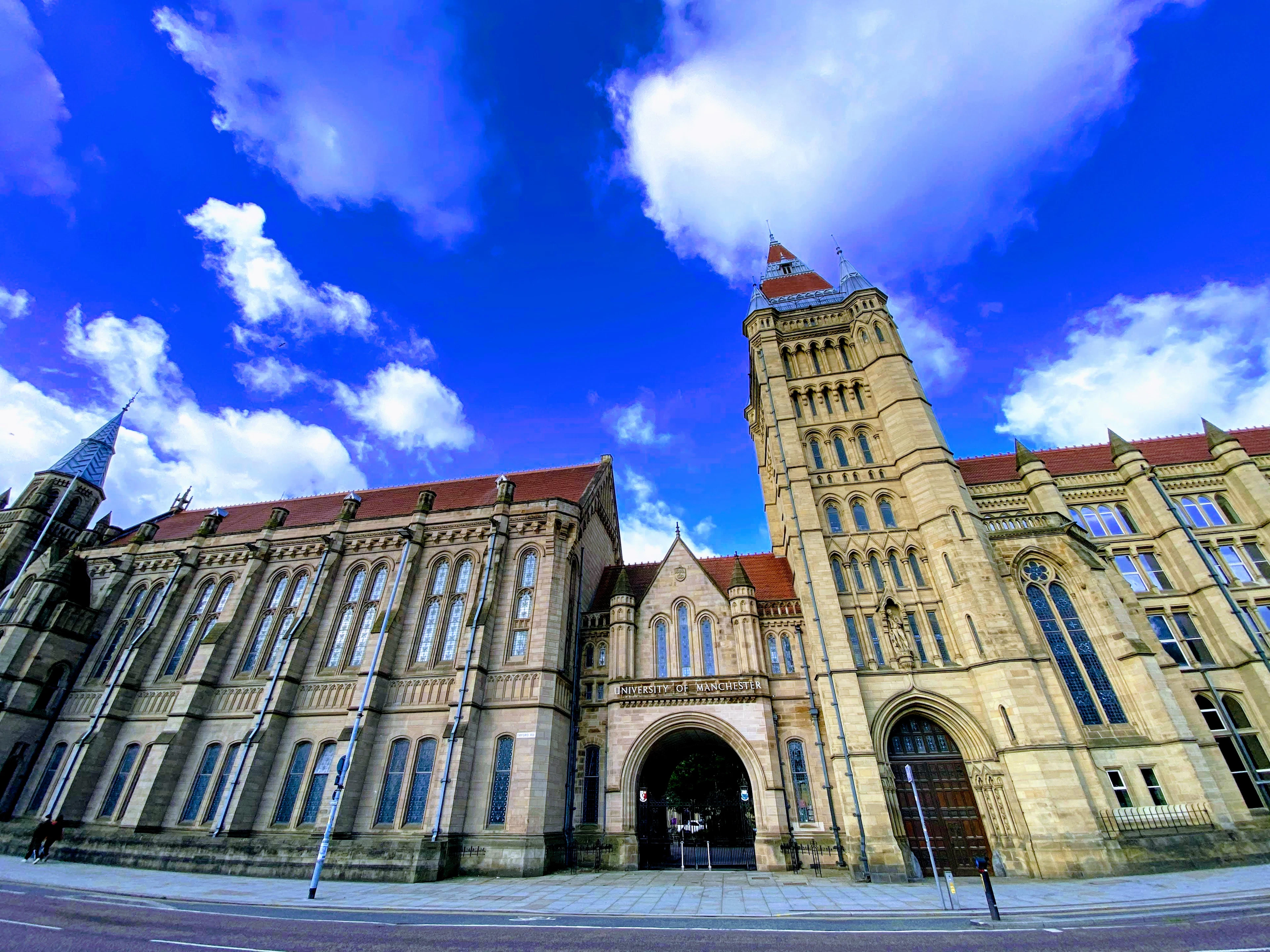 Gothic Revival university building with a red-topped tower against a vivid blue sky