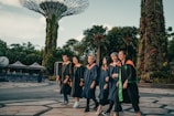 group of people in black academic dress standing on gray concrete pavement during daytime